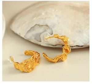Macro detail of gold irregular lava texture earrings with secure silicone backs on seashell