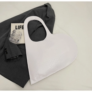 Detailed view of white heart-shaped bag with crocodile pattern and stylish accessories