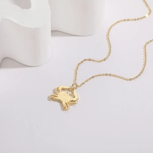 Detail view of 14K gold plated crab pendant necklace with shell zircon on a white stand