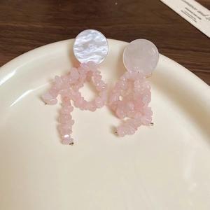 Detail of pink natural stone tassel earrings with white shell pieces on a ceramic tray