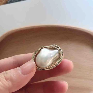 Macro detail of Baroque irregular white pearl ring with golden handmade wire wrap