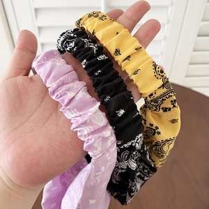 Set of three elastic paisley bandanas in purple, black, and yellow fabric texture