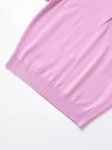 Close-up of pink knit polo shirt featuring fine texture and ribbed hem detail