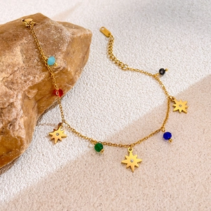 Detail view of gold star bracelet with multi-color beads on natural stone background