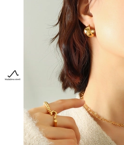 Detail view of 18K gold plated stainless steel C-shaped earrings and rings on a model