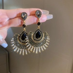 Gros plan sur les boucles d'oreilles vintage dorées avec cristaux noirs et pompons