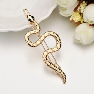 Detail of a gold snake-shaped hair clip with diamond accents and textured metal surface