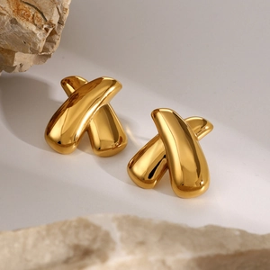 Detail of 18k gold plated stainless steel chunky X-shaped earrings on light stone