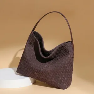 Detailed view of dark brown hand-woven leather hobo bag texture on a white pedestal