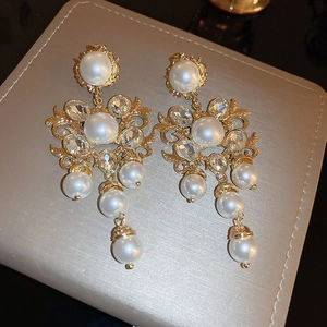 Gros plan détaillé des boucles d'oreilles baroques avec perles et glands en cristal