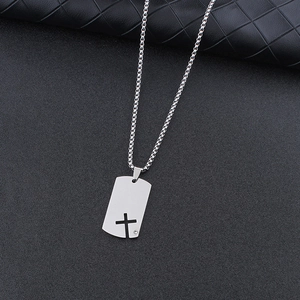 Detail of silver box chain necklace with hollow cross dog tag pendant and small rhinestone