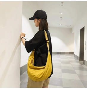 Vue latérale d'un grand sac bandoulière en nylon jaune porté par un mannequin