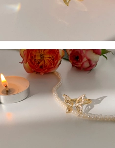 Detailed view of a gold butterfly ring with white zircon wings on pearls and flowers