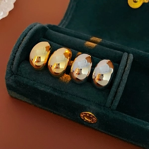 Macro shot of minimalist gold and silver bean-shaped C-earrings in a green velvet box