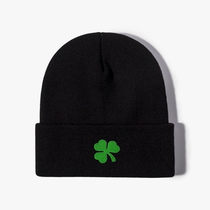 Close-up of green clover embroidery on black knitted beanie with detailed wool texture