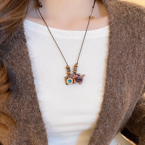 Detail of wooden cat and camera pendant on a long brown cord sweater necklace
