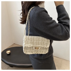 Detailed close-up of a green tweed crossbody bag featuring a golden chain strap on a model