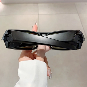 Detail of matte black futuristic Y2K sunglasses with unique crossover temple design