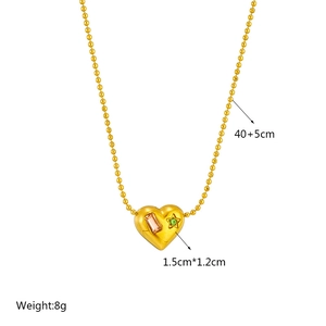 Minimalist gold beaded necklace with heart pendant featuring pink and green gems