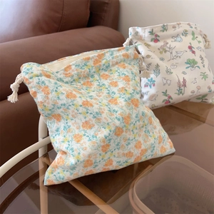 Gros plan de deux pochettes de rangement en coton à fleurs et à cordon posées sur une table