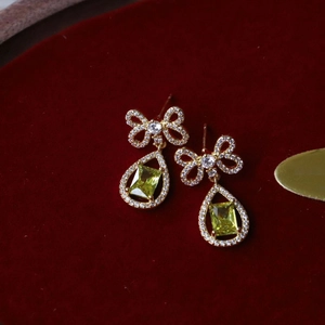 Macro view of bowknot drop earrings with zircon stones on red velvet background