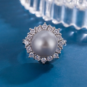 Elegant sunflower ring with gray pearl and zircon accents on a textured blue surface