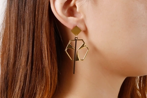 Close-up of geometric hollow gold and black titanium steel drop earrings on a model