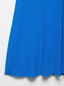 Dettaglio di abito in maglia blu acceso con trama a pieghe e bordo smerlato rifinito