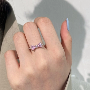 Macro shot of bow ring with two pink heart-shaped stones and silver diamond band