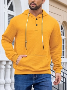 Close-up of yellow men's waffle knit hoodie showing button neck and textured fabric