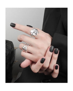 Close-up of irregular textured silver rings on a model with matte black nails