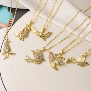Elegante collar con colgante de pájaro dorado y cristales sobre fondo de seda blanca