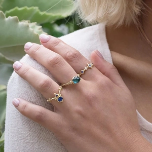 Close-up of model wearing gold-plated S925 silver rings with blue opal and small diamonds