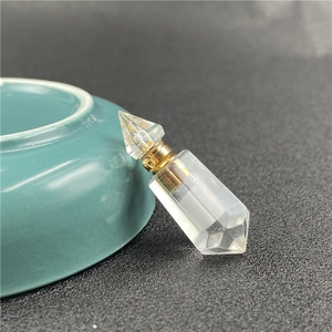 Close-up of hexagonal faceted clear crystal perfume bottle pendant with golden metal cap