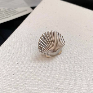 Detailed macro view of two-tone shell ear cuff featuring elegant metallic ribbed texture
