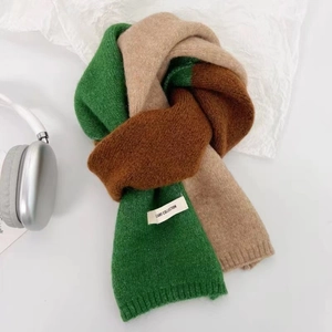 Détail d'une écharpe en maille bicolore verte et marron avec étiquette Scarf Collection