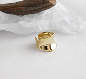 Detail eines breiten unregelmäßigen Goldrings mit glänzendem Finish auf Texturoberfläche