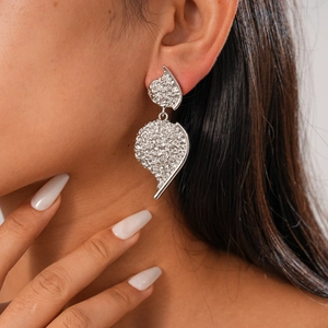 Detail showing irregular textured silver heart earrings worn by a model in close-up shot