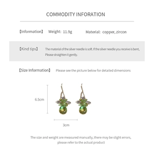 Detail view of gold earrings with green zircon flowers and teardrop pendants