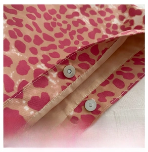 Detailed close-up of metal magnetic buckle on pink leopard print canvas bag