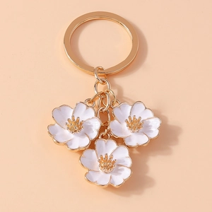 Detail view of white cherry blossom pendant keychain with gold-plated metal edges and links