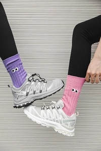 Detail of pink and purple ribbed crew socks featuring cartoon eye embroidery on the ankle