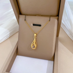 Macro view of a gold teardrop pendant with a clear gemstone in a beige gift box
