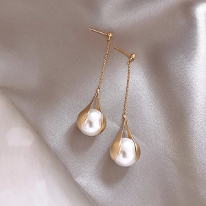 Detail of C-shaped drop earrings featuring white pearls and zircon on gray silk