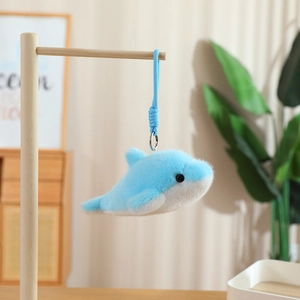 Cute blue plush dolphin keychain pendant with soft fur texture on a wooden stand