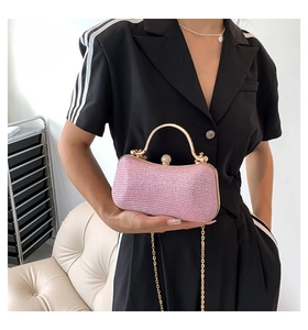 Detailed shot of pink glitter evening clutch with gold metal handle and rhinestone clasp