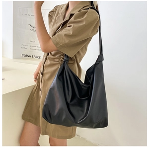 Detail view of large black leather hobo bag with unique knotted strap and soft draped design