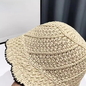 Detail of hand-woven straw bucket hat with beige texture and black wave crochet trim