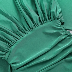 Dettaglio dell'abito in raso verde smeraldo con eleganti pieghe e trama di tessuto setoso