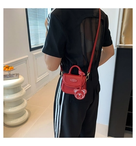 Red mini saddle bag for women featuring a cute bear charm and adjustable shoulder strap